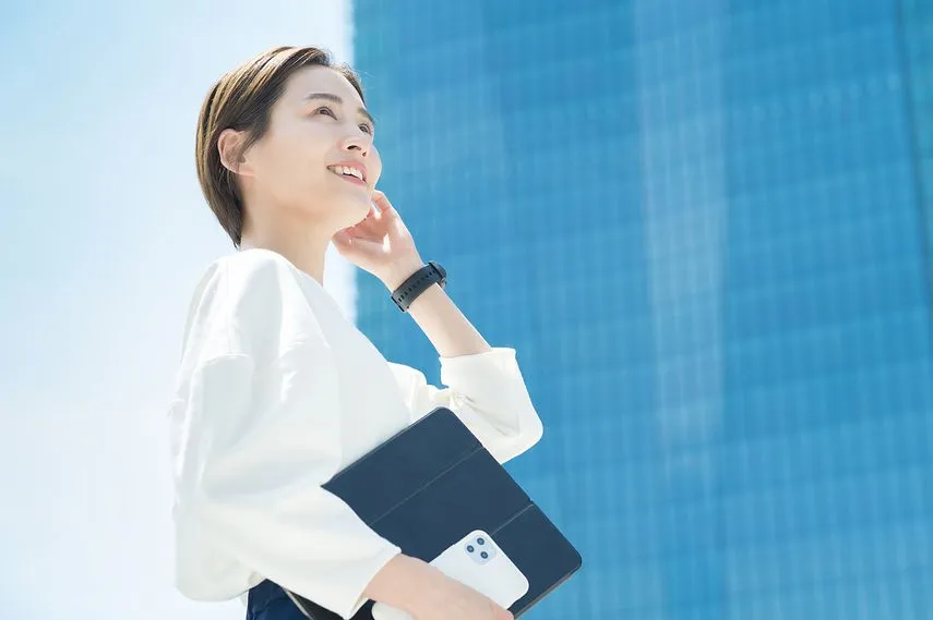 オフィス街に立つ笑顔の女性