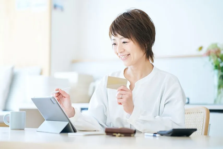 カードを持ってタブレットPCを操作する女性