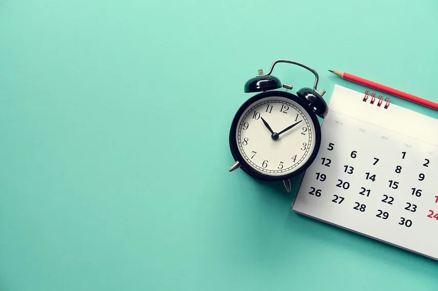 close up of calendar and alarm clock on the green background, planning for business meeting or travel planning concept