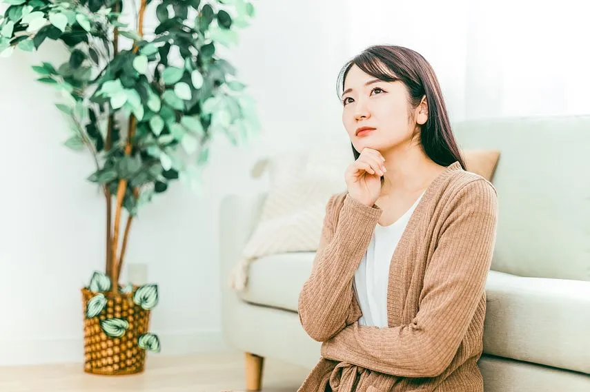 ソファの下に座るパジャマ姿の女性（考える）