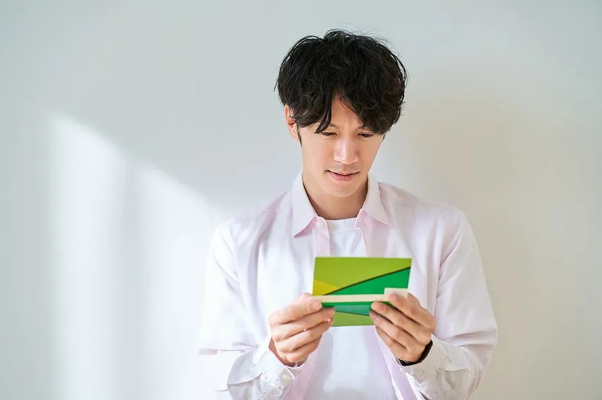 通帳を見て、がっかりする若い男性