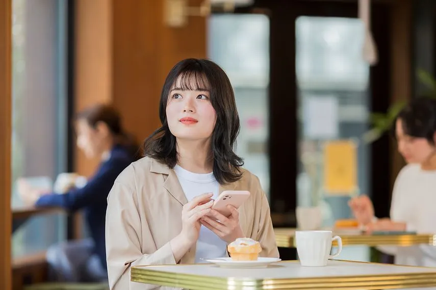 カフェでスマホを見る若い女性