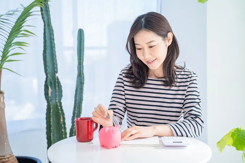 明るいリビングで貯金箱に貯金する女性