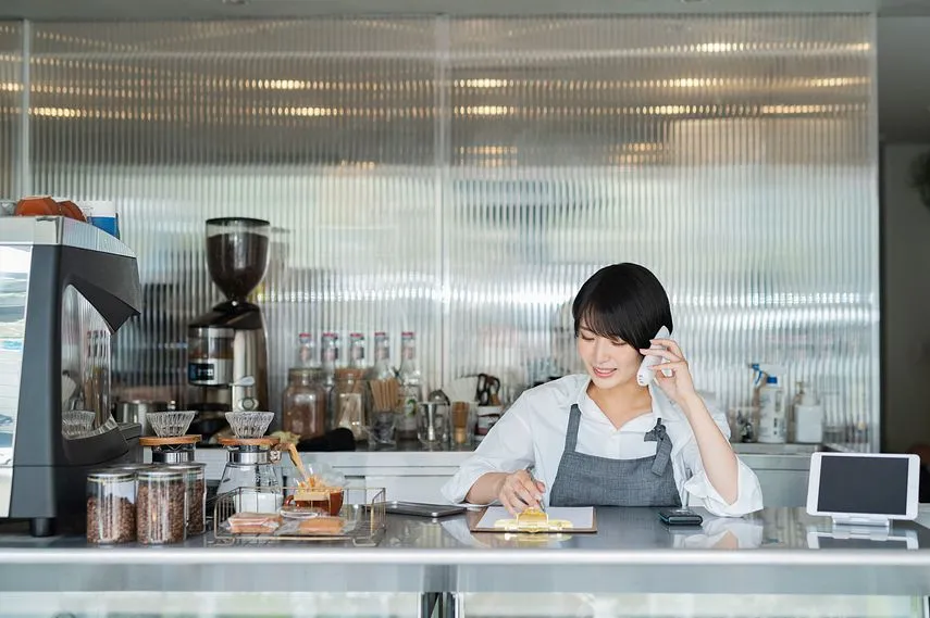 カフェ 電話をする女性スタッフ