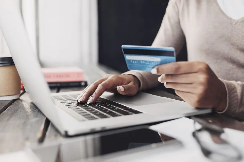Online payment. Closeup of woman hands using laptop computer and holding credit card, young businesswoman working at home, online shopping, e-commerce, internet banking, finance and freelance concept