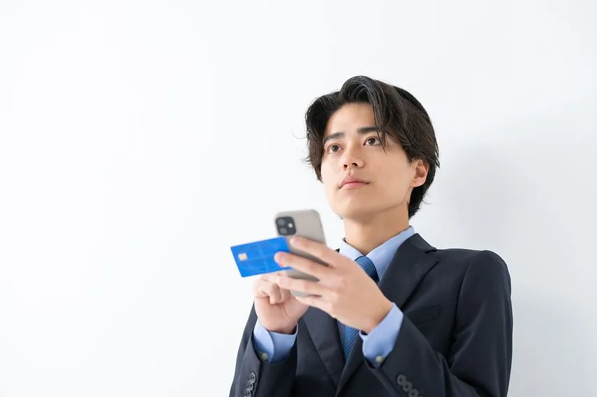 クレジットカードとスマートフォンを使うビジネス男性