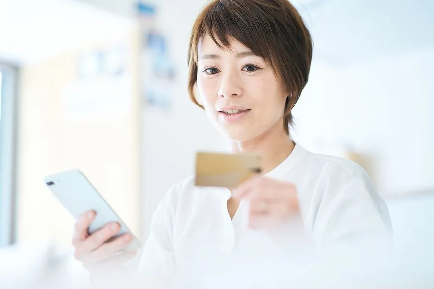 カードを持ってスマートフォンを操作する女性