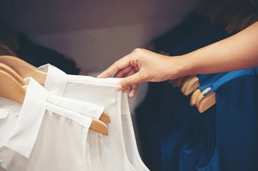 店内で服を選んでいる客の手