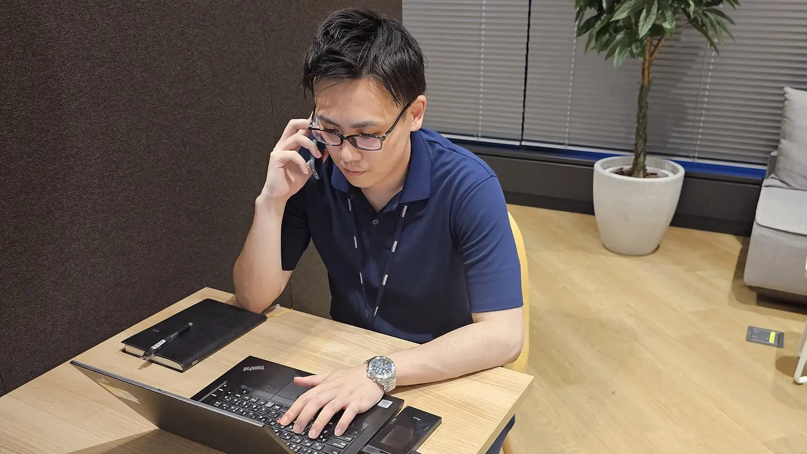 電話をしながらPCで作業をしている松田さん