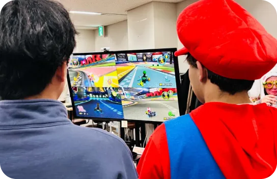 ファミリーデーにゲームキャラクターに扮した社員が一緒にテレビゲームを興じる