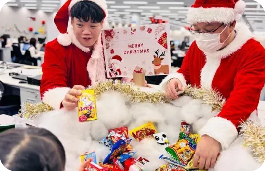 ファミリーデーでサンタクロースに扮装して子どもにお菓子を手渡す社員2名