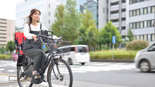 自転車に跨り保育園へお迎えに行く社員