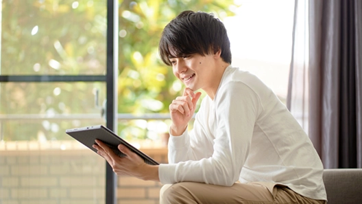 会社以外の場所でタブレットを片手に椅子へ座る様子